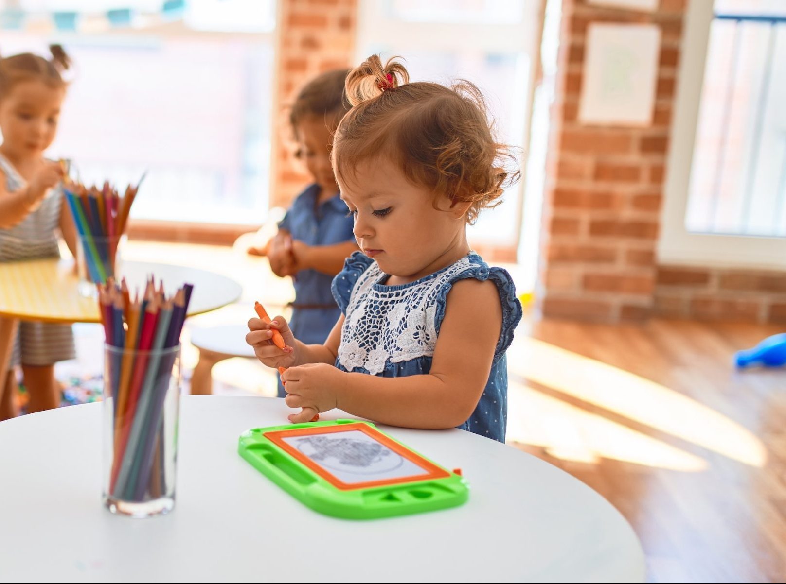 teacher and group of toddlers playing around lots of toys